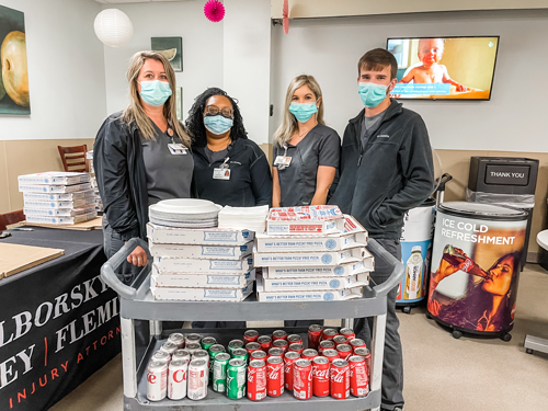 Photo of the firm's legal professional along with the container of pizzas and cokes Gulf Coast Regional Medical Center Pizza Day